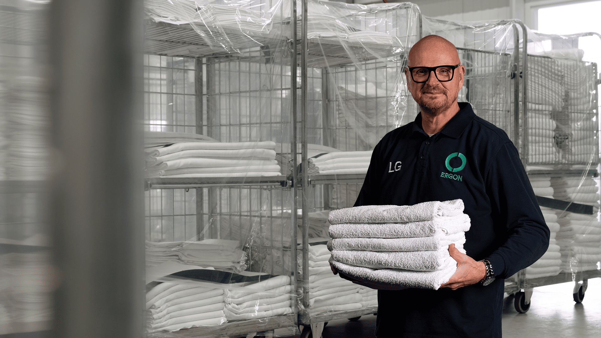 Medewerker staat met stapel handdoeken in wasserij